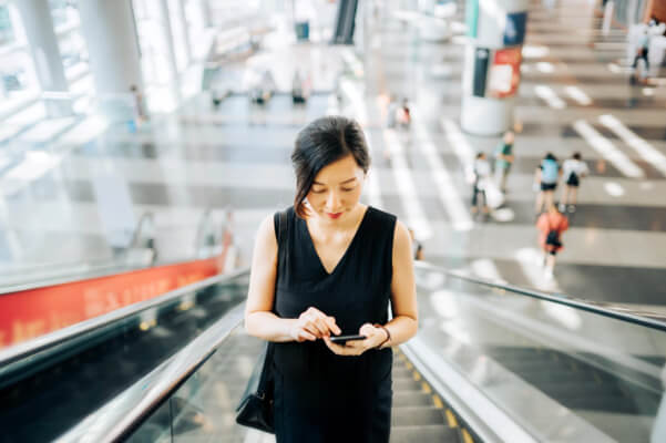 Dame med mobiltelefon i rulletrapp