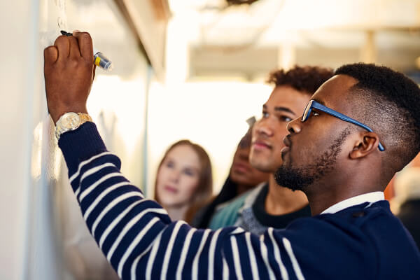 Gruppe personer som ser på / noterer på en tavle