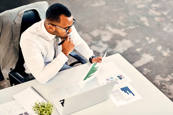 Mann ved skrivebord ser på grafer på et ark